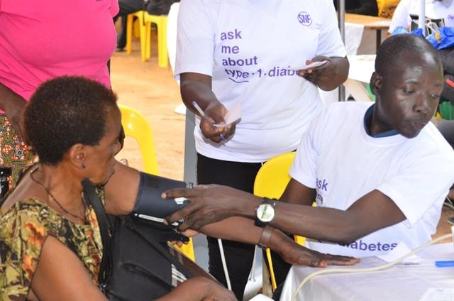 A health worker records a blood pressure reading for a woman seated beside him.