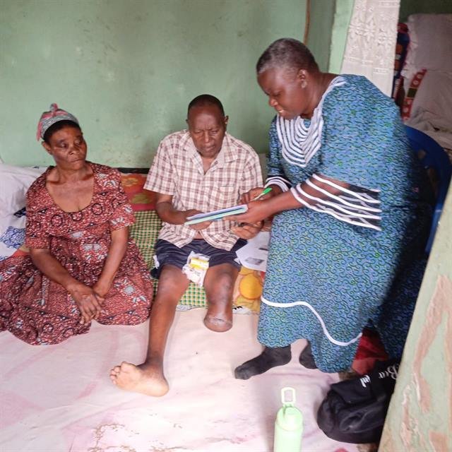 An RDAF team member records notes during a home visit while family members sit alongside.